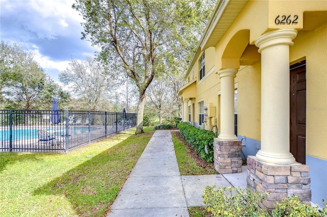 exterior space with a swimming pool, fence, and a lawn