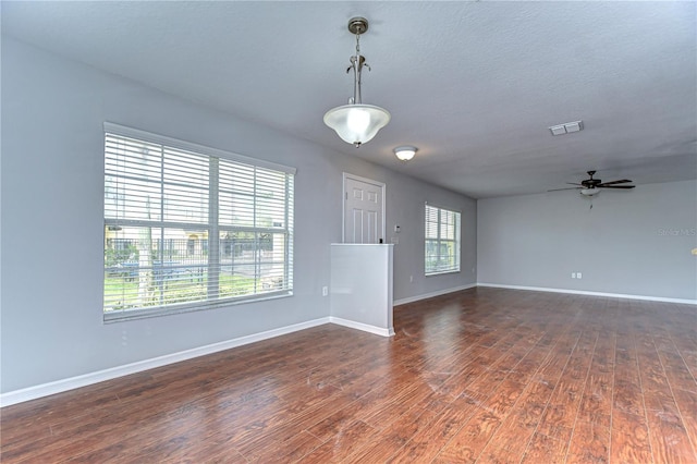 spare room featuring baseboards, visible vents, dark wood finished floors, ceiling fan, and a textured ceiling