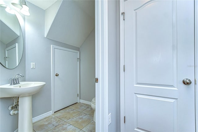 bathroom featuring baseboards, a sink, toilet, and tile patterned floors