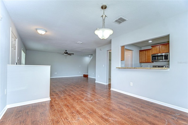 unfurnished living room with ceiling fan, wood finished floors, visible vents, and baseboards