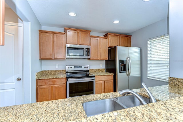 kitchen featuring brown cabinets, appliances with stainless steel finishes, a sink, and recessed lighting