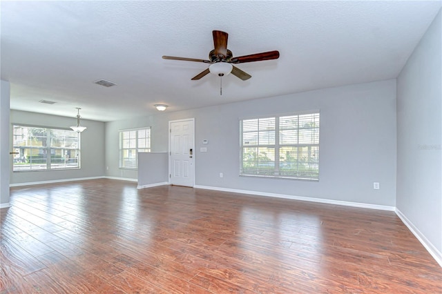 unfurnished living room with visible vents, dark wood finished floors, baseboards, and ceiling fan