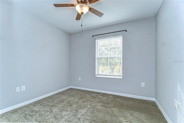 carpeted spare room featuring a ceiling fan and baseboards