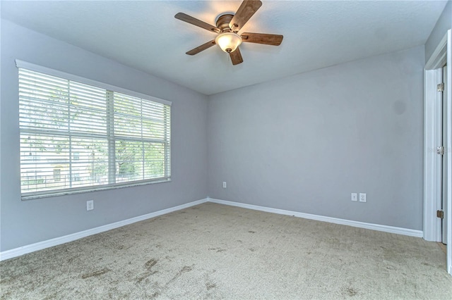 carpeted spare room with ceiling fan and baseboards