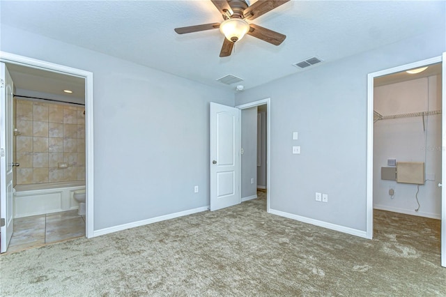 unfurnished bedroom featuring a walk in closet, carpet, a closet, visible vents, and baseboards