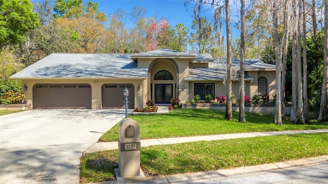 view of front of house with a garage, a front yard, driveway, and stucco siding