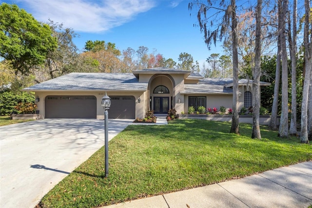 ranch-style house featuring a garage, a front lawn, concrete driveway, and stucco siding