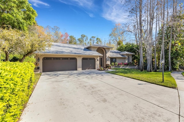 view of front of home featuring a garage, driveway, a front lawn, and stucco siding