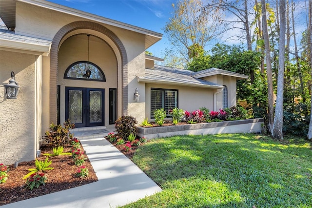 property entrance with a yard, french doors, and stucco siding