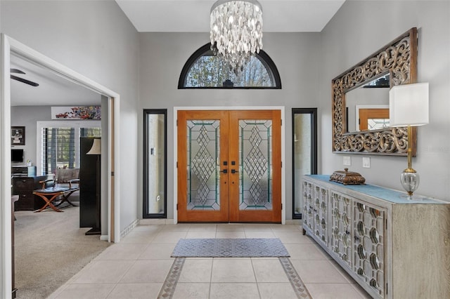 foyer with a chandelier, french doors, baseboards, and light tile patterned floors