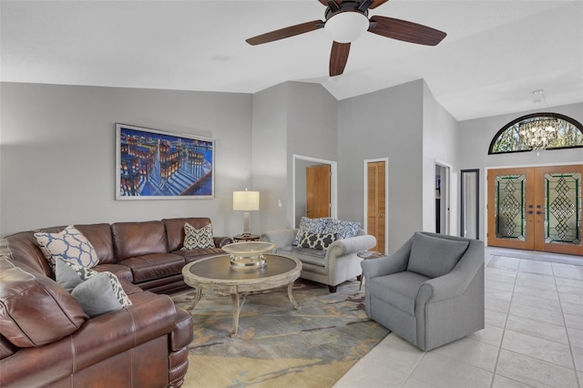 tiled living room featuring ceiling fan with notable chandelier, high vaulted ceiling, and french doors