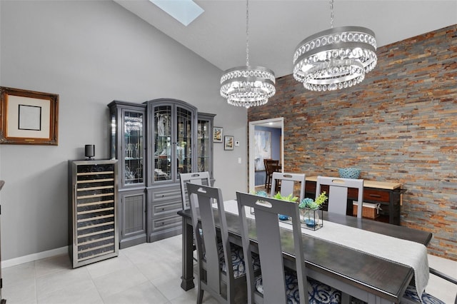 dining room featuring light tile patterned floors, beverage cooler, a skylight, high vaulted ceiling, and a chandelier