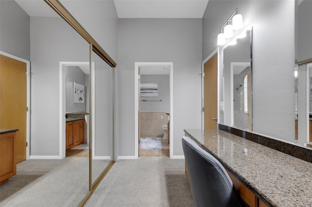 bathroom with carpet flooring, walk in shower, vanity, and baseboards