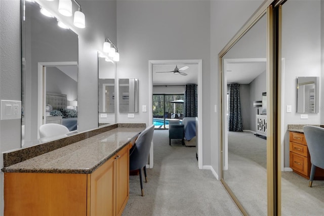 bathroom featuring baseboards, ceiling fan, vanity, and ensuite bath