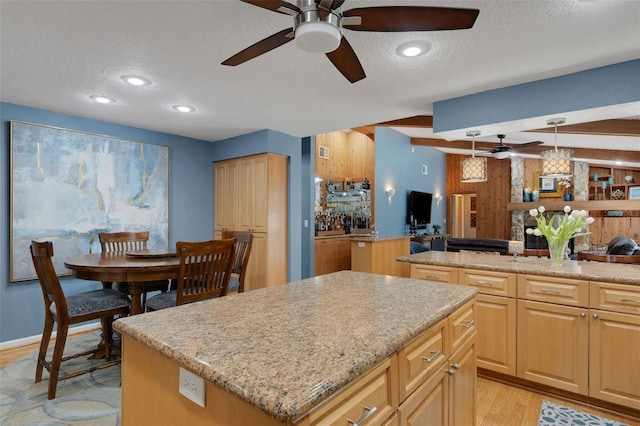 kitchen with light stone counters, open floor plan, a textured ceiling, and a center island