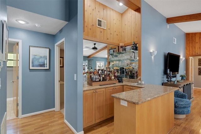 bar featuring visible vents, light wood-style flooring, beamed ceiling, wet bar, and a sink