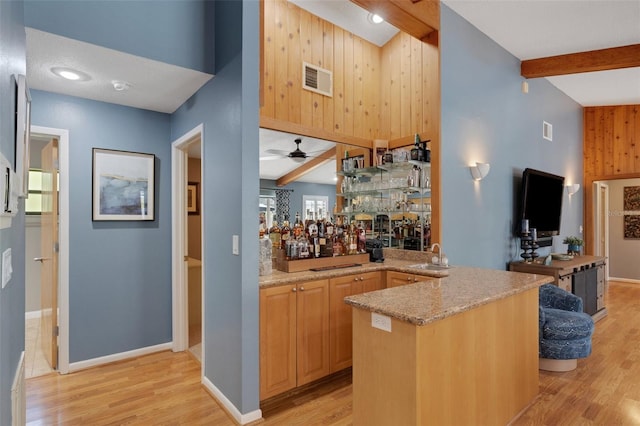 interior space featuring visible vents, light wood-style flooring, beamed ceiling, wet bar, and a sink