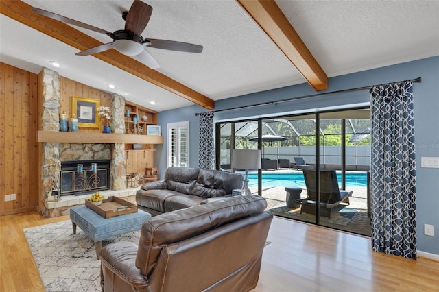 living area featuring vaulted ceiling with beams, a sunroom, a textured ceiling, and wood walls