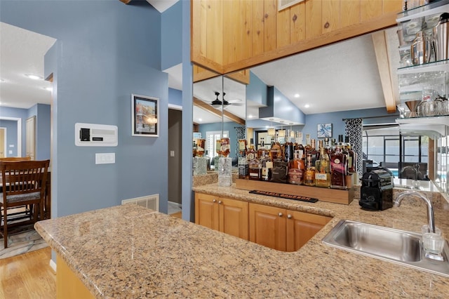 bar featuring visible vents, a ceiling fan, a sink, light wood-type flooring, and indoor wet bar