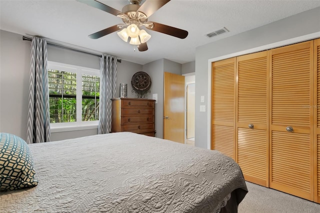 carpeted bedroom featuring ceiling fan, a closet, and visible vents