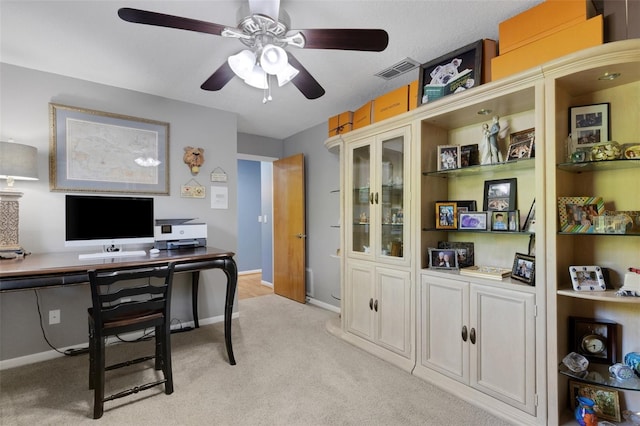 home office with baseboards, visible vents, a ceiling fan, and light colored carpet