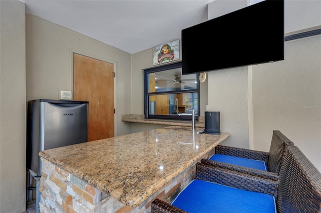 kitchen featuring light stone counters and freestanding refrigerator