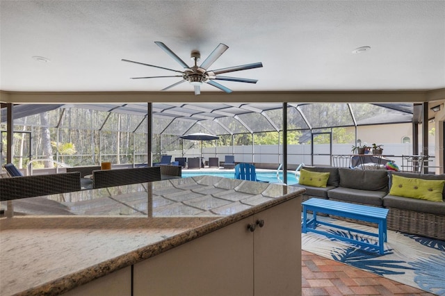 view of patio with glass enclosure, a ceiling fan, an outdoor living space, outdoor dry bar, and a fenced in pool