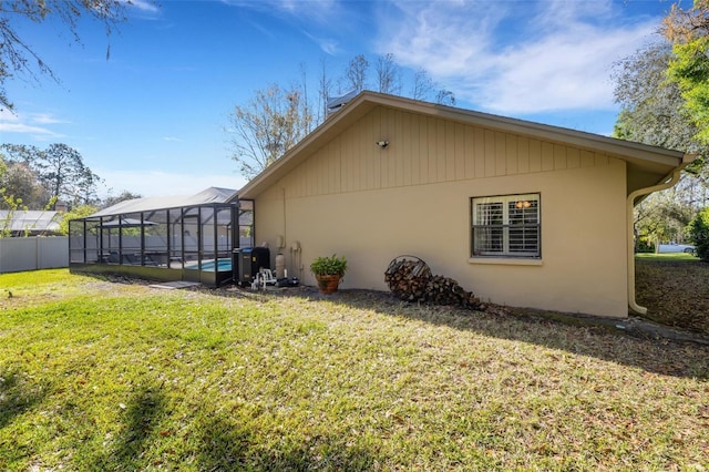 view of side of home with a lanai, fence, and a lawn