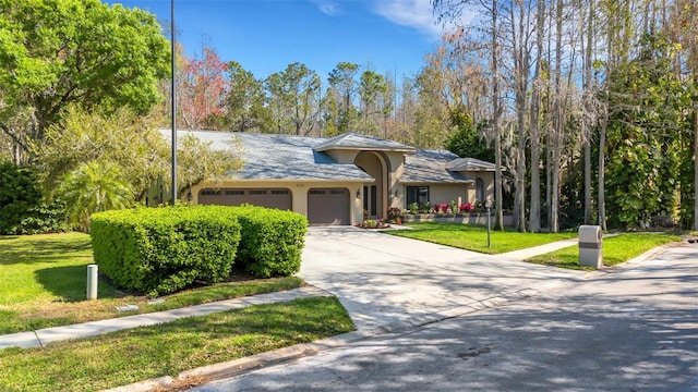 view of front of house featuring a garage, driveway, a front lawn, and stucco siding