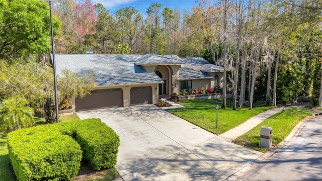 view of front of property with a garage, driveway, a front lawn, and stucco siding