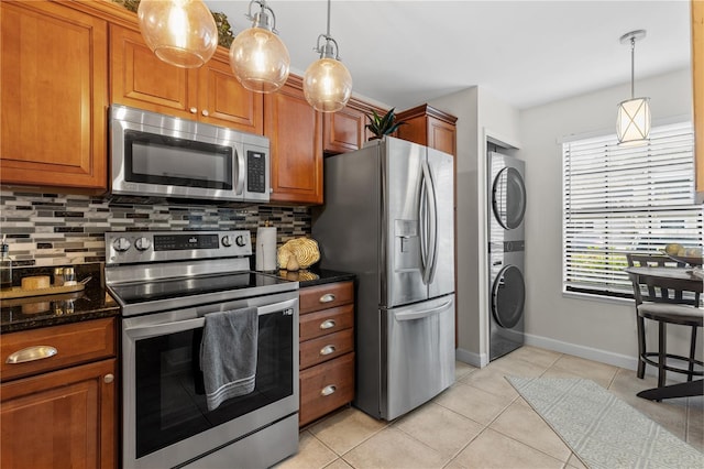 kitchen featuring appliances with stainless steel finishes, stacked washer / dryer, and brown cabinetry