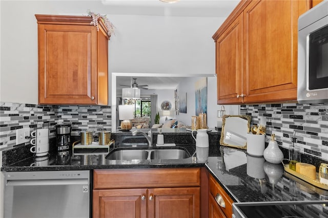 kitchen with stainless steel appliances, dark stone countertops, a sink, and brown cabinets