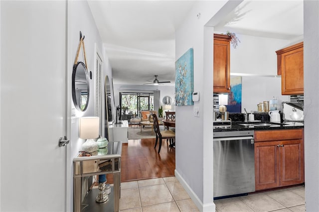 kitchen with light tile patterned floors, a ceiling fan, baseboards, stainless steel dishwasher, and brown cabinets