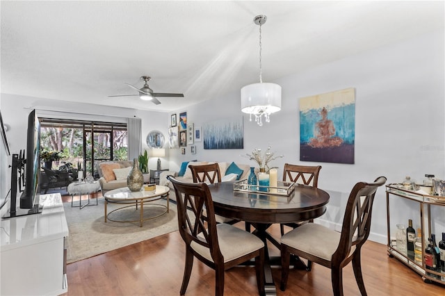 dining room featuring ceiling fan with notable chandelier, baseboards, and wood finished floors