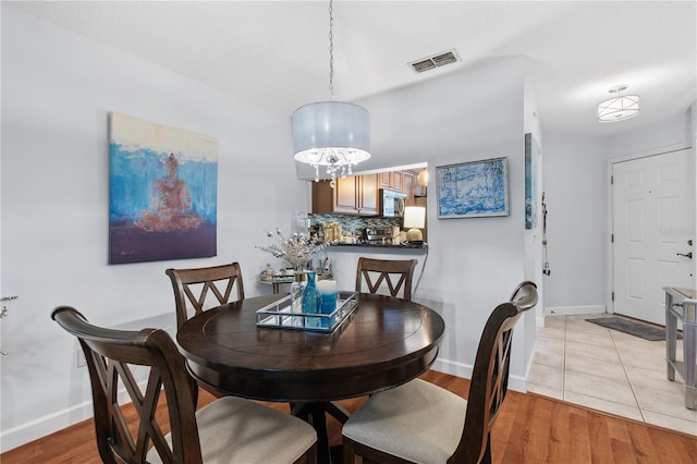 dining space with light wood-type flooring, visible vents, and baseboards