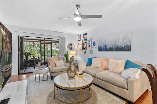 living area with ceiling fan, a textured ceiling, and wood finished floors