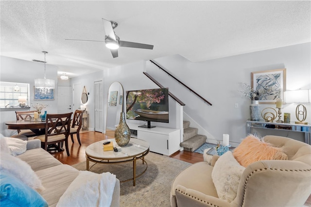 living area with wood finished floors, a textured ceiling, baseboards, and stairs