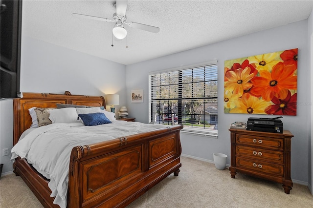 bedroom with light carpet, ceiling fan, baseboards, and a textured ceiling