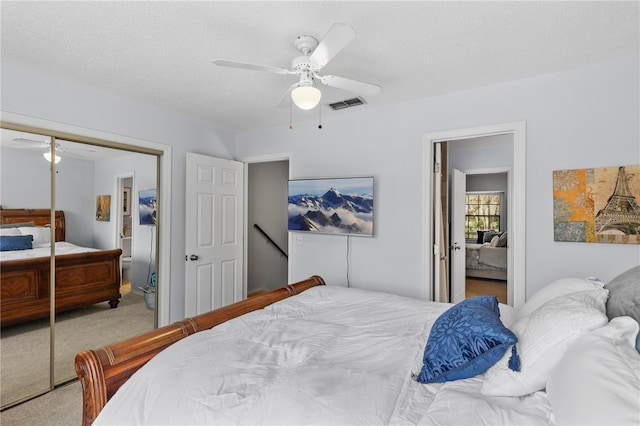 carpeted bedroom with a closet, visible vents, ceiling fan, and a textured ceiling