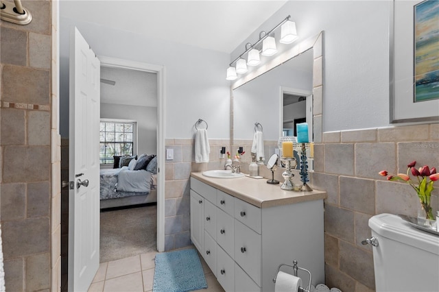 ensuite bathroom featuring tile walls, toilet, vanity, ensuite bath, and tile patterned floors