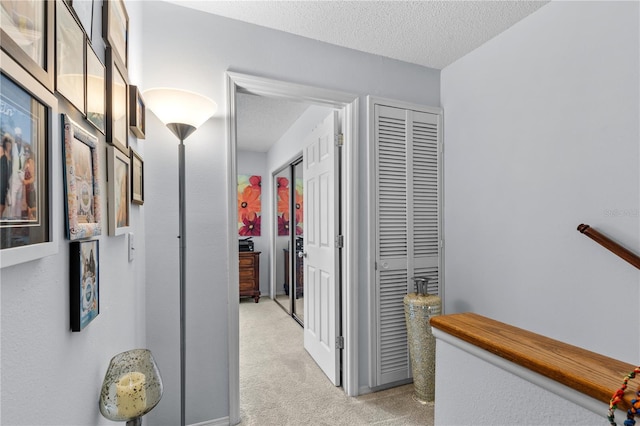 corridor with light carpet and a textured ceiling