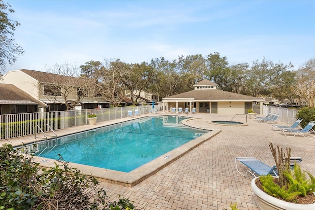 pool with a patio area, fence, and a hot tub