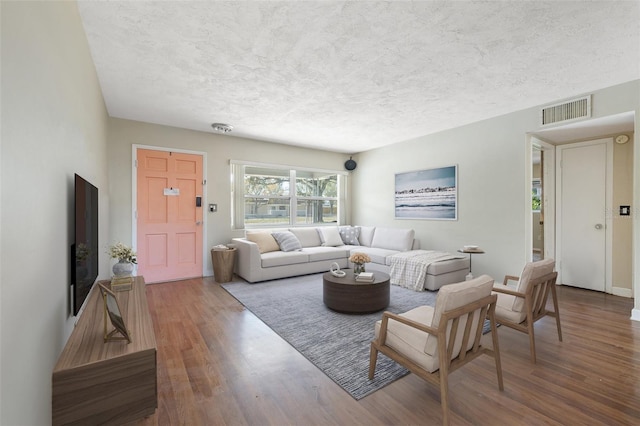 living room featuring a textured ceiling, wood finished floors, and visible vents