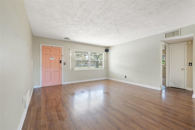 foyer entrance featuring baseboards, a textured ceiling, visible vents, and wood finished floors