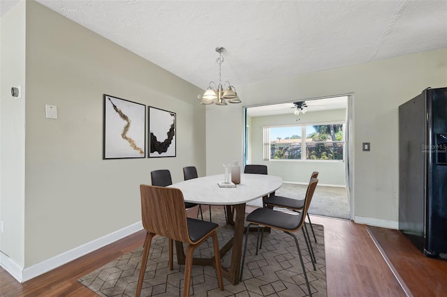 dining area featuring a chandelier, a textured ceiling, wood finished floors, and baseboards