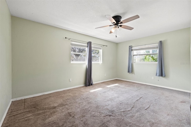 carpeted spare room with a textured ceiling, baseboards, and a ceiling fan