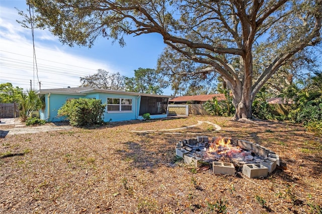 view of yard featuring an outdoor fire pit, fence, and a sunroom