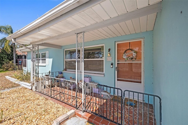 view of exterior entry with fence and a porch