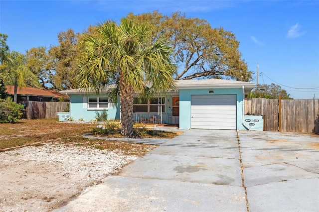 single story home with a garage, concrete driveway, fence, and stucco siding