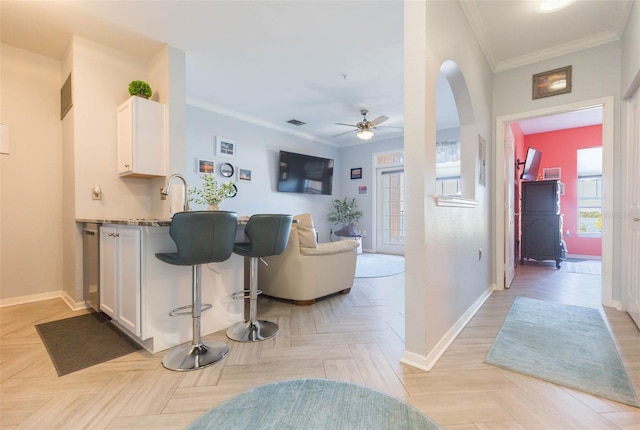 interior space with crown molding, visible vents, a sink, ceiling fan, and baseboards